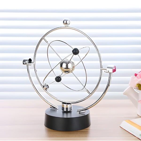 Detalhe do movimento cinético orbital do pêndulo AstroZen Nomanni, objeto decorativo que transmite equilíbrio visual e sensação de calma.