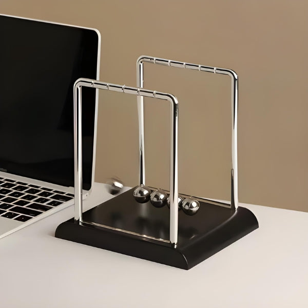Detalhe do pêndulo de equilíbrio Newton com esferas metálicas, objeto decorativo clássico que transmite harmonia, lógica e concentração no escritório.