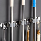 Suporte adesivo multiuso em inox para organização de vassouras, rodos e utensílios, sem necessidade de furar a parede.
